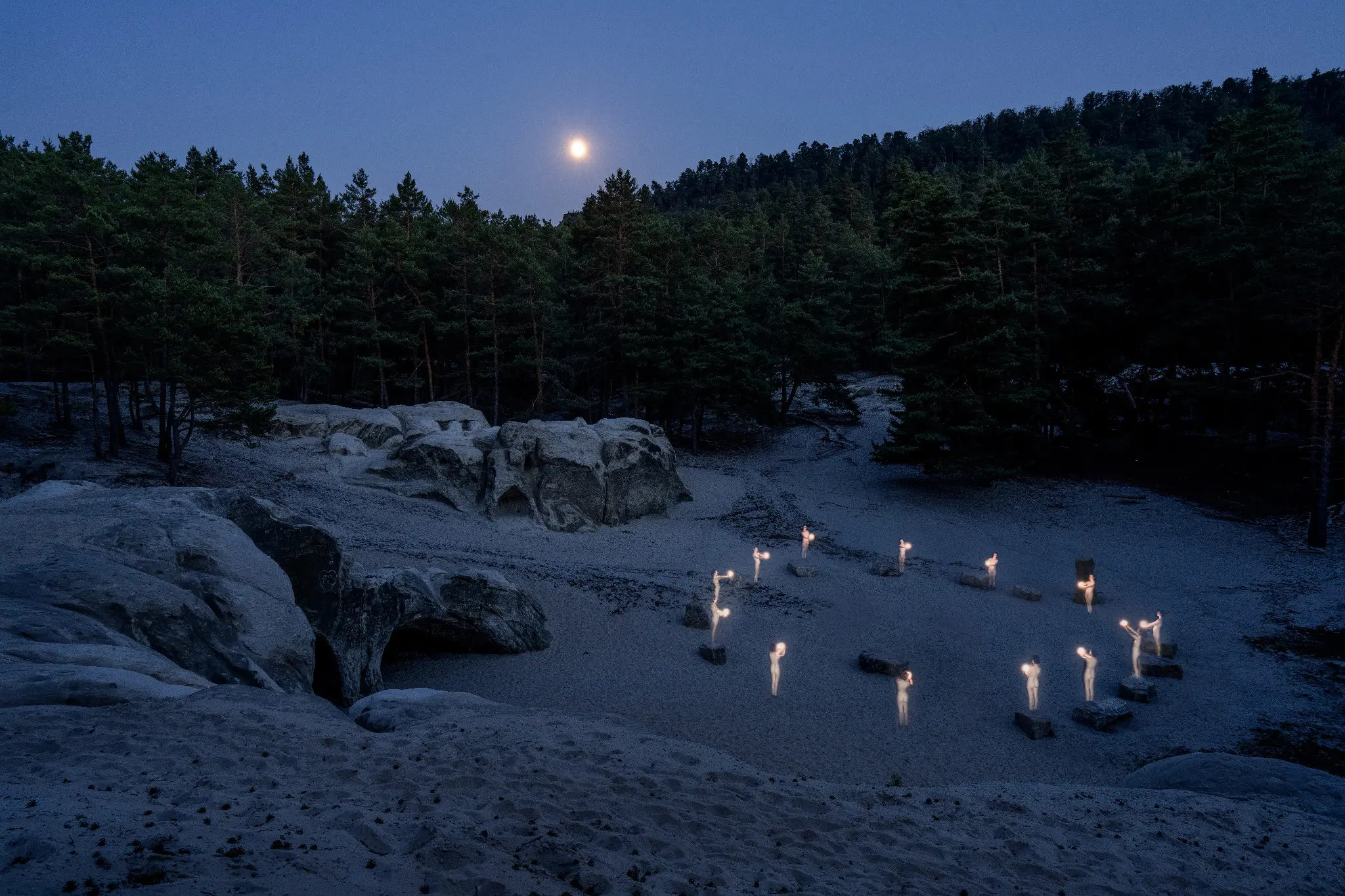 Vervielfachte lichttragende Figuren in einer mondbeschienenen Felslandschaft
